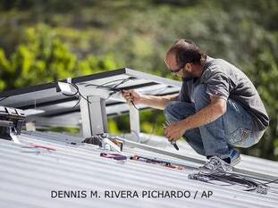  A technician installs a solar energy system at a home in Adjuntas, Puerto Rico, in July 2018.