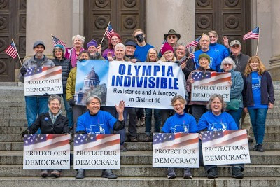 Olympia Indivisible members on the Capitol steps with signs saying “Protect Our Democracy”