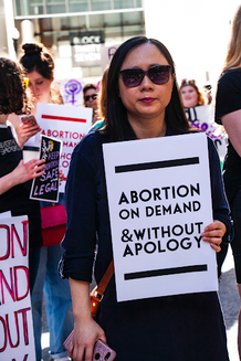 Woman holding protest sign for Abortion on Demand & Without Apology