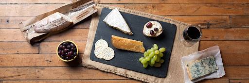 Cheeseboard with olives, grapes, cheese, crackers, baguette and a glass of wine.